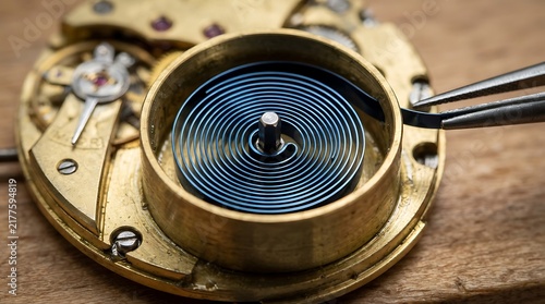 Macro shot of a professional watchmaker repairing a vintage mechanical movement by adjusting the coiled mainspring with precision tweezers