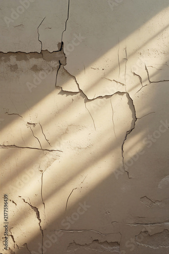 Minimalist background of cracked beige concrete wall with shadows