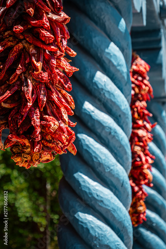 Bright red ristras hang between turquoise spiral columns in Taos, New Mexico