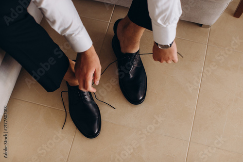 Foto Groom tying black leather shoes for wedding ceremony