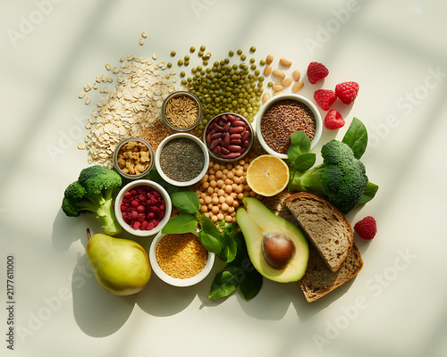 Assorted healthy superfoods with grains seeds legumes and fresh fruits on light surface