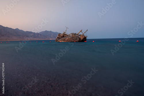Quadro su tela Wide shot of an abandoned rusty cargo shipwreck submerged in the calm waters of