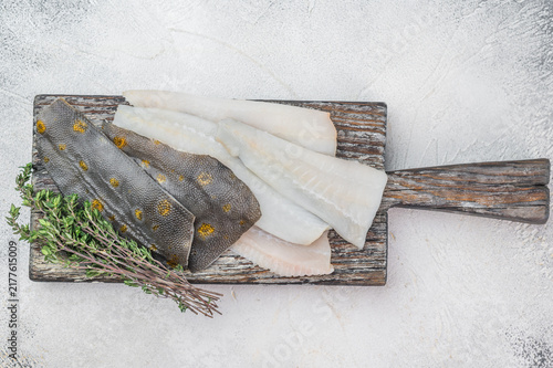 Quadro su tela Fresh plaice flatfish fillets with herbs and garlic on wooden cutting board, raw