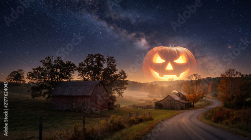 Glowing jack-o’-lantern moon rises over a quiet rural farmhouse and winding road beneath a star-filled Halloween night sky.