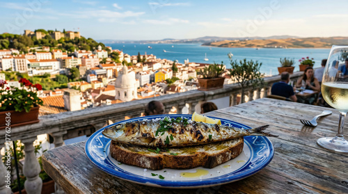 Grilled fish served with herbs and lemon at a scenic seaside restaurant overlooking a coastal town and blue Aegean waters.