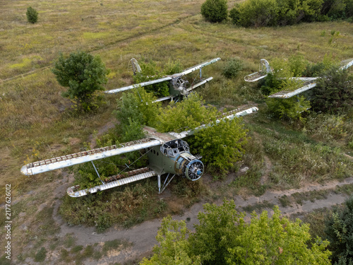 Aerial view of abandoned AN-2 aircrafts with signs of decay in overgrown summer airfield