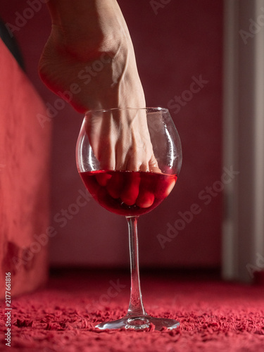 Obraz na płótnie Foot fetish. A woman dips her toes in a glass of red wine.