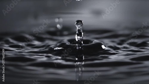Water droplet falling and splashing into liquid surface. Slow motion, liquid dynamics, physics, nature, clean design.