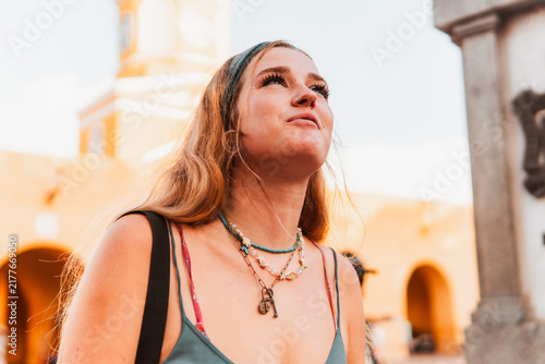 Young woman traveler looking up in wonder, exploring an ancient colonial city street, discovering historical architecture during a cultural trip