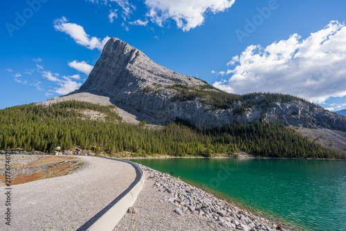 Whitemans Pond reservoir green water and concrete dam with Ha Ling Peak mountain. Canmore, Alberta, Canada.