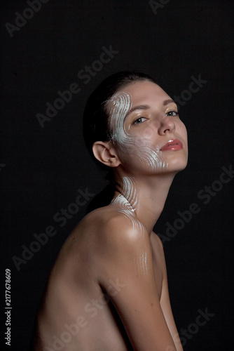 Fotografie A portrait of a nude young woman with white artistic makeup on her face and neck