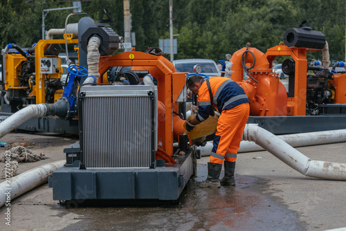 Worker on maintenance of pump machine for cleaning street sewer manholes