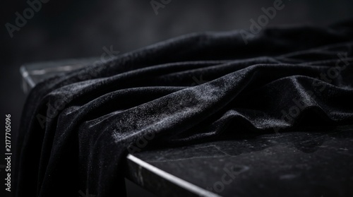 Close Up Texture of Elegant Black Velvet Fabric Draped Over Dark Marble Table

