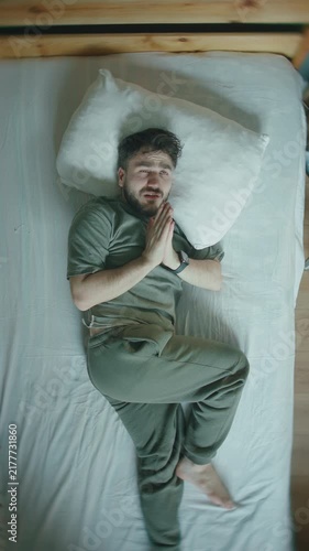Man lying in bed praying with folded hands before falling asleep, top view ,vertical video