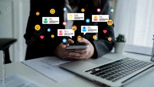 A person holds a smartphone surrounded by vibrant social media notification icons  depicting communication and engagement in a contemporary office setting. Ledger