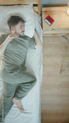 Man reaching to turn off alarm clock in bed, early morning wake up struggle ,vertical video