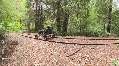 Mature couple enjoys riding an electric railbike over old railroad tracks in a forest of redwood trees near Mendocino.