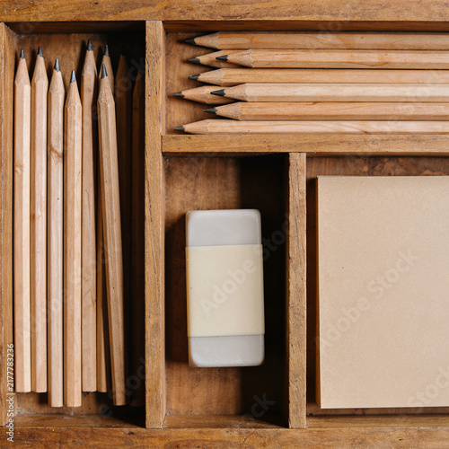 Wooden desk organizer with pencils, eraser and paper, warm art supplies still life