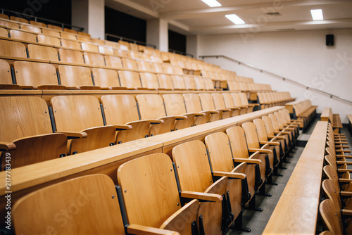 Spacious empty auditorium with tiered light wooden seats in amphitheater layout