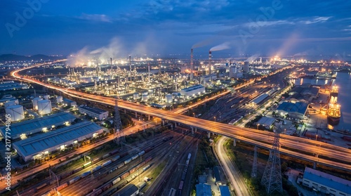 Aerial view of a large industrial oil refinery and chemical plant with a highway and railway tracks at night