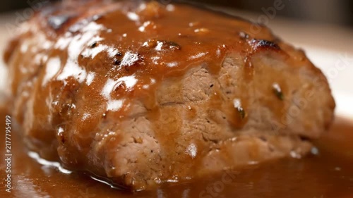Macro Close-up of Succulent Roasted Pork Tenderloin or Loin Steak Smothered in Rich Brown Gravy or Sauce, Highlighting Appetizing Glazed Texture of Gourmet Meat Dish.