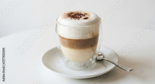 Layered coffee drink topped with froth and cocoa powder