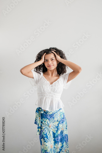 Teenage girl running fingers through curly hair, smiling confidently