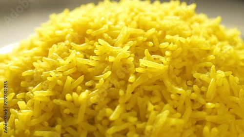 Macro Close-up of Fluffy, Vibrant Yellow Rice Piled High, Showing Detailed Grain Texture.