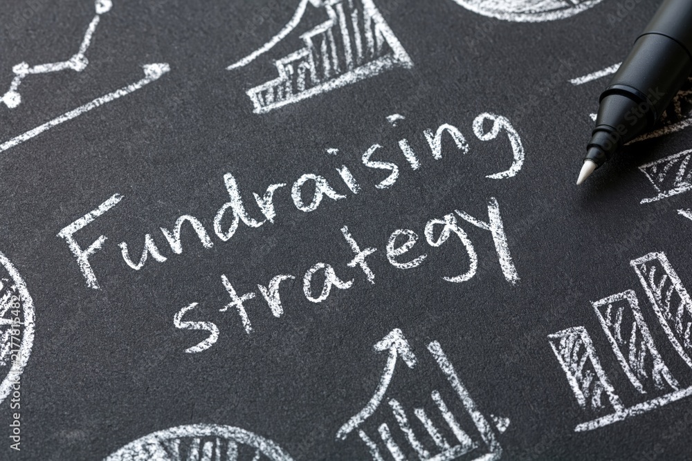 Fototapeta premium Fundraising strategy written on a chalkboard with business finance planning growth development capital investment