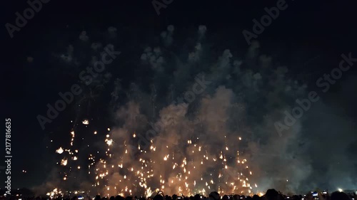 Spectacular fireworks display illuminating the night sky above a silhouetted crowd during a festive celebration.