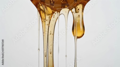 Closeup of golden honey dripping from a honey dipper with detailed texture and slow-motion footage