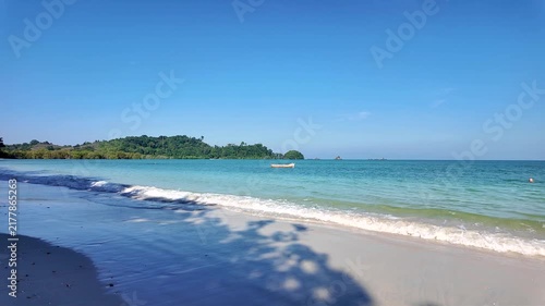 An idyllic tropical beach with the calm movement of the sea waves and a lonely fishing boat.