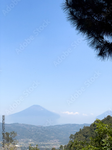 Foto A distant mountain peak rises above hazy hills under a clear blue sky