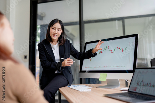 Young woman discussing business analytics and charts, managing finance and cryptocurrency trading in a modern office