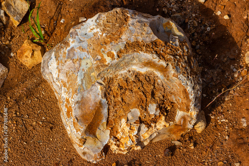 Cuadro en lienzo Large textured chert boulder resting on raw clay earth of an open pit quarry, sh