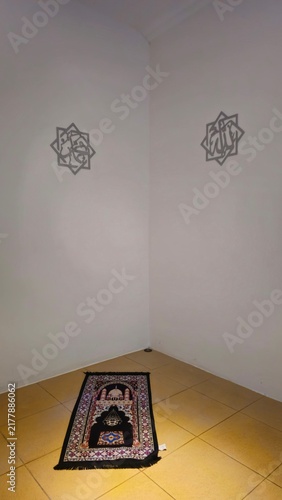 Foto Islamic prayer rug placed on a tiled floor in a quiet minimalist room, with geometric wall artwork and warm ambient lighting creating a peaceful spiritual atmosphere