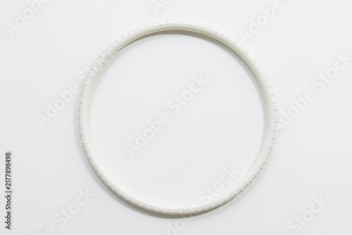 A white circular frame or ring with a textured surface, placed against a minimalist white background.