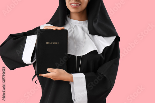Canvastavla Young nun with Bible on pink background