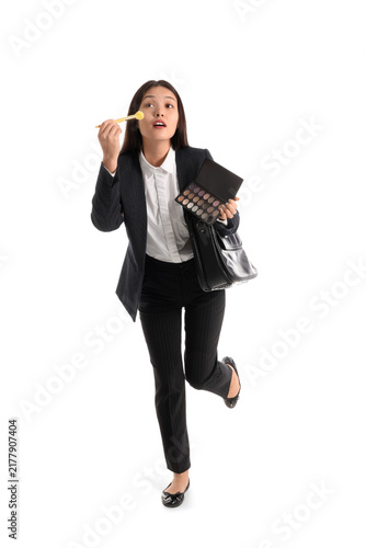 Funny Asian businesswoman with briefcase applying makeup on white background