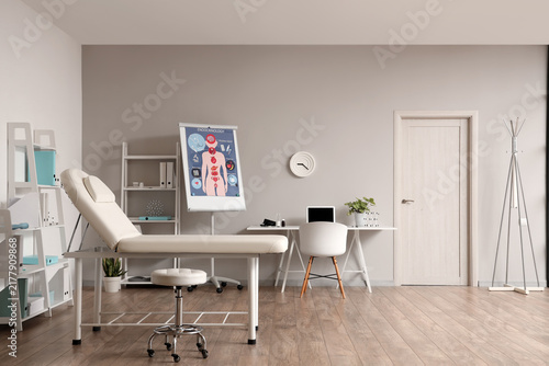 Interior of medical office with workplace, couch and shelf units