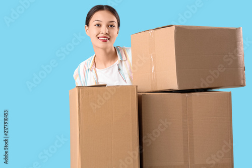 Young Asian woman with parcels on blue background