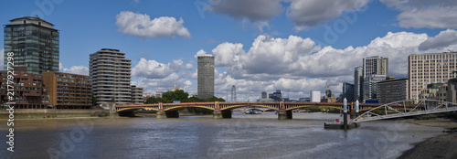 Photography Downstream view along the River Thames from Chelsea Embankment in London, featuring river traffic, Grosvenor Railway Bridge and the modern Vauxhall skyline beneath dramatic storm clouds