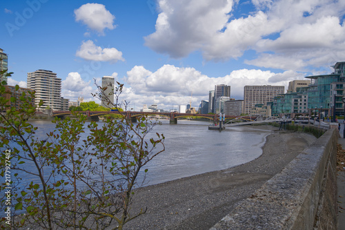 Obraz na plátně Downstream view along the River Thames from Chelsea Embankment in London, featuring river traffic, Grosvenor Railway Bridge and the modern Vauxhall skyline beneath dramatic storm clouds