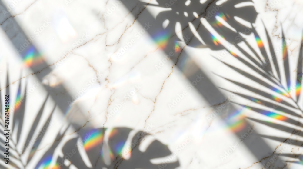 Obraz premium Tropical leaf shadows with vibrant rainbow light refractions on a pristine white marble background, creating a serene and aesthetic summer atmosphere
