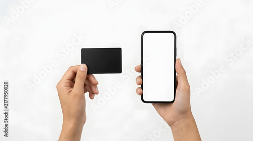 Two hands holding a black rectangular card and a smartphone with a blank white screen against a plain white background, minimalist style featuring black card, blank screen, mobile phone and device