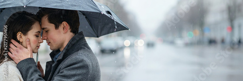 A couple embracing under a black umbrella on a rainy day in the city, with blurred streetlights and traffic in the background