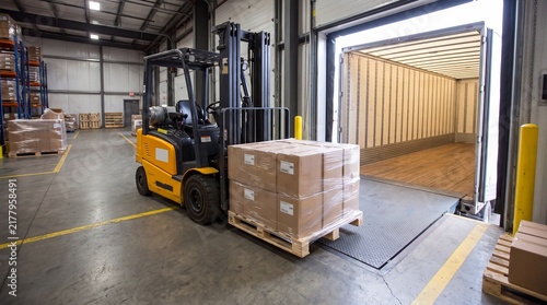 Industrial Forklift Operator Placing Cardboard Cargo Into Freight Trailer