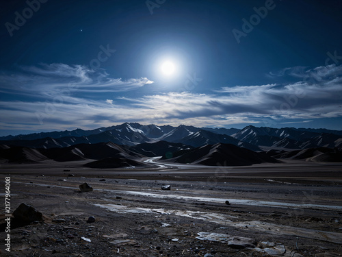 Snow-capped mountains and sand dunes under moonlight