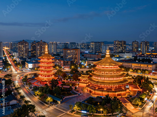 Ancient towers illuminated against a modern city skyline at night