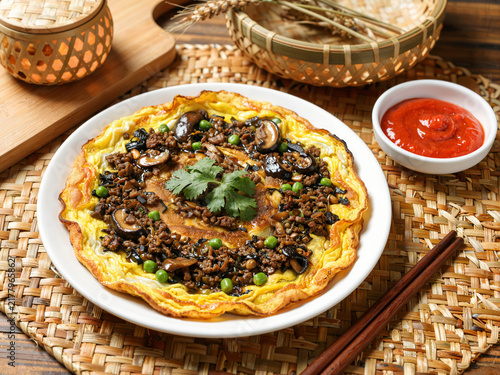 Chinese-style egg pancake with meat sauce and mushrooms served on a wo